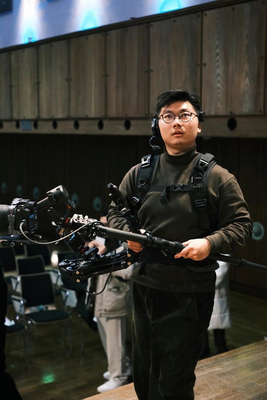 Jikang (Calvin) Yu operating a cinema camera with a body-support rig